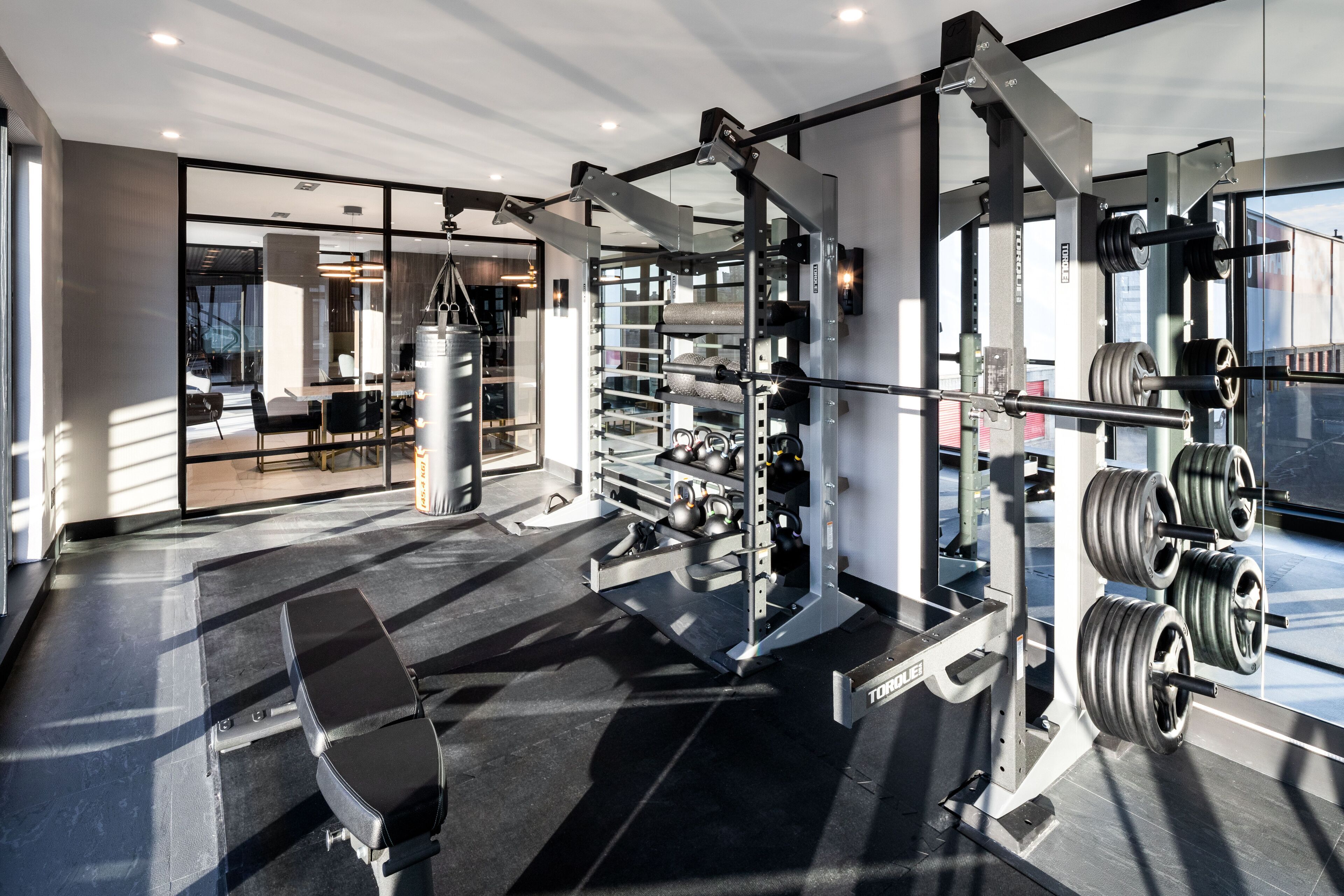 Une salle de sport moderne équipée de matériel de musculation, d’un banc et d  ’un sac de frappe.