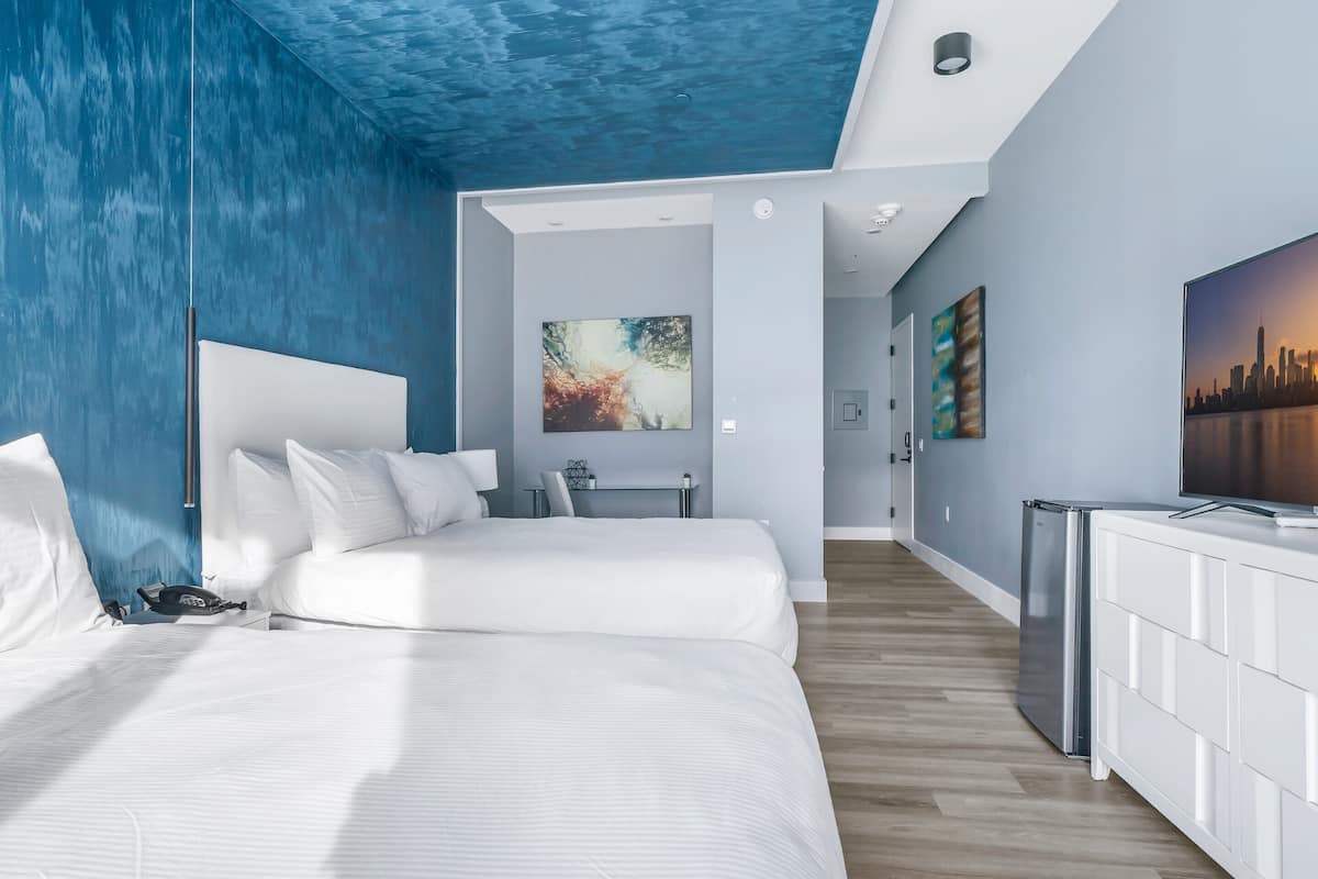 Une chambre d’hôtel moderne équipée d’un lit, d’une table de chevet et d’un bureau avec une chaise.