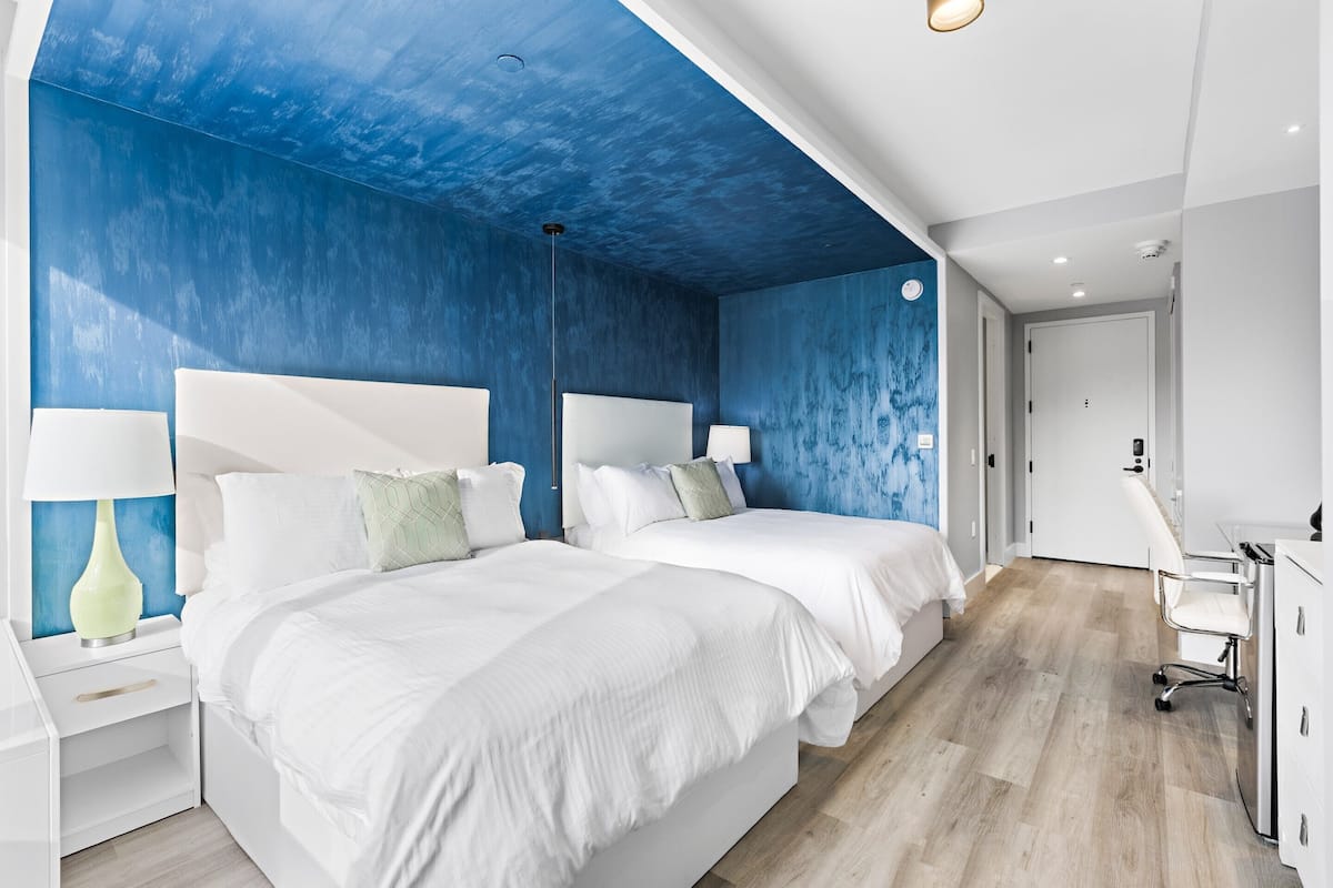 Une chambre d’hôtel moderne avec deux lits, un bureau et une chaise.