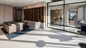 Een moderne woonkamer met een bank, fauteuils, een salontafel en een ingebouwde boekenkast.