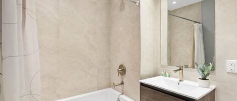 A modern bathroom with a bathtub, a vanity with a sink, and a large mirror.