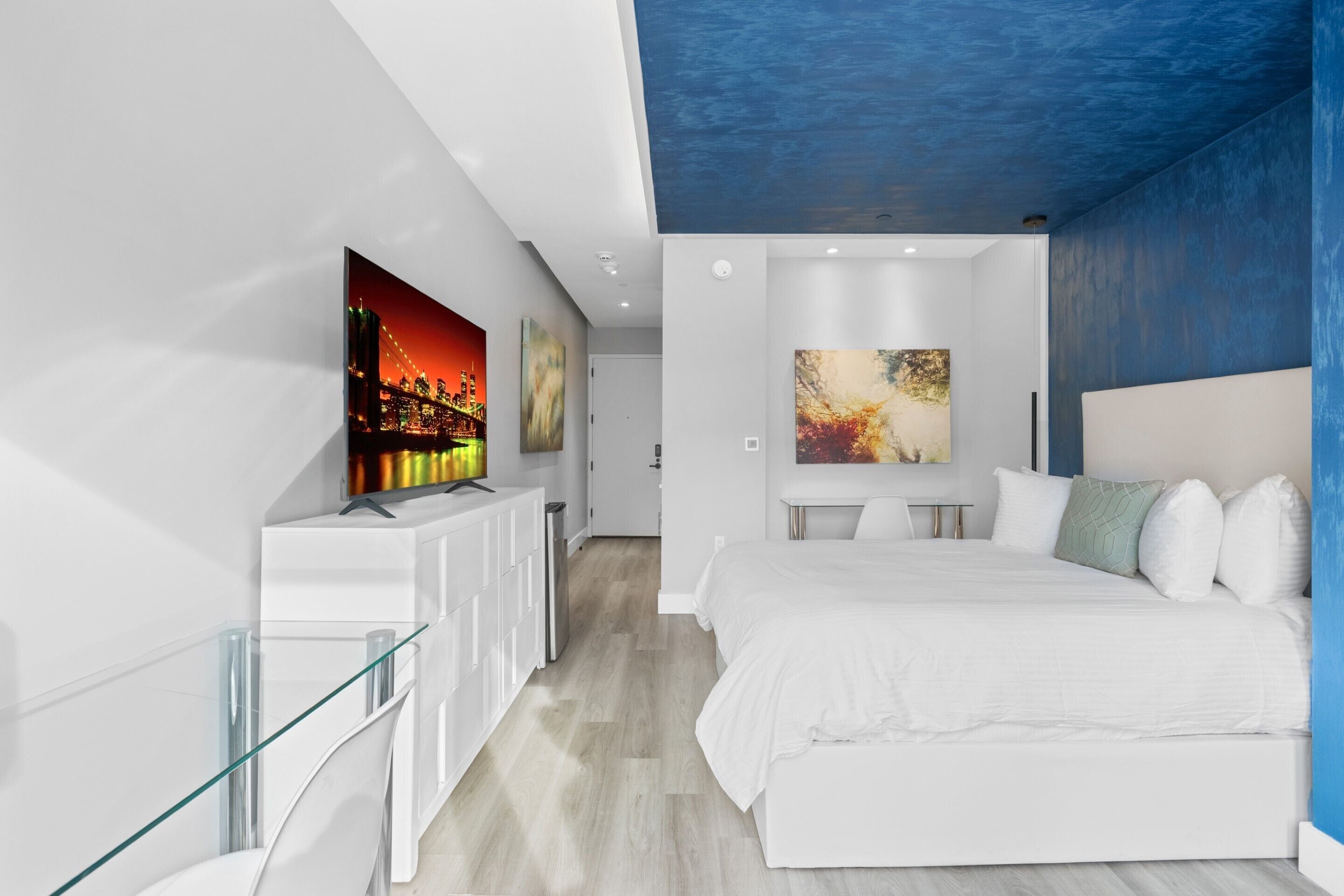 Ein modernes Schlafzimmer mit einem großen Bett, einem Glastisch und zwei Bildern an der Wand.