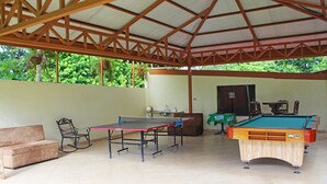 A covered outdoor area with a ping pong table, pool table, and a sofa. - Apartment 8: Condos Vista al Volcan - Second Floor (La Fortuna)