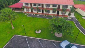 A multi-story building with a red-tiled roof, surrounded by well-maintained lawns and palm trees. - Apartment 8: Condos Vista al Volcan - Second Floor (La Fortuna)
