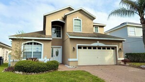 A two-story house with a garage, a large window, and a well-maintained lawn. - Relax in style! Close to parks - TVs every room - Modern kitchen - near golf. (Davenport)
