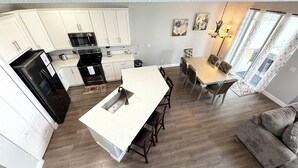 A modern kitchen with white cabinets, a black stove, and a central island. - Relax in style! Close to parks - TVs every room - Modern kitchen - near golf. (Davenport)