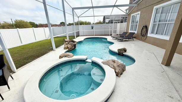 A backyard with a swimming pool, a hot tub, and a covered patio area. - Relax in style! Close to parks - TVs every room - Modern kitchen - near golf. (Davenport)