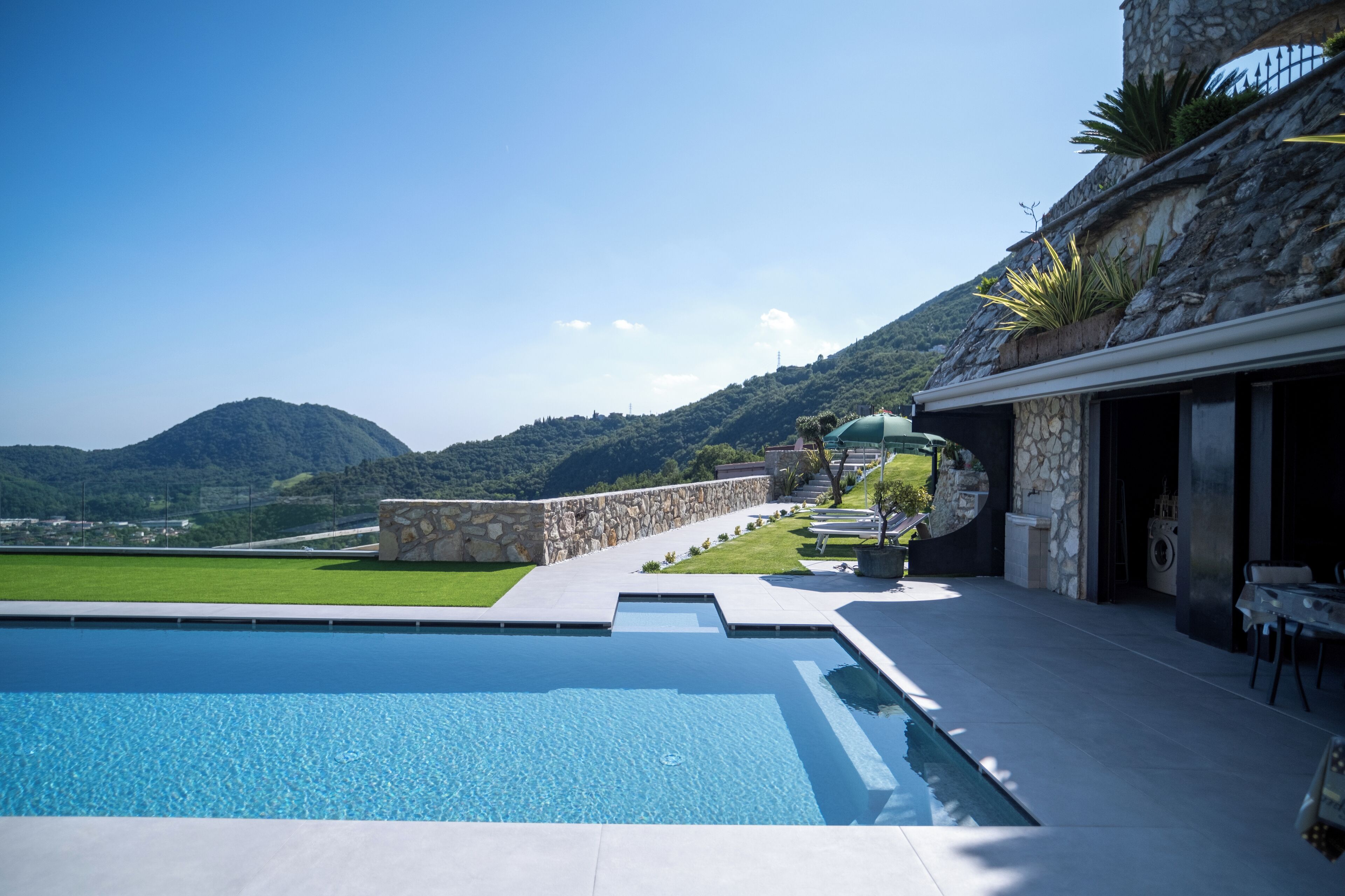 Une piscine avec un mur en pierre et une vue sur les montagnes.