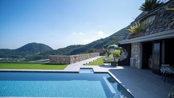 Ein Pool mit Steinmauer und Blick auf Berge.