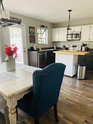 A kitchen with a wooden island, white cabinets, stainless steel appliances, and a blue upholstered chair.