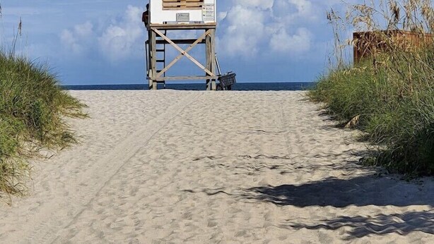Una torre de salvavidas en una playa arenosa con cielo despejado.
