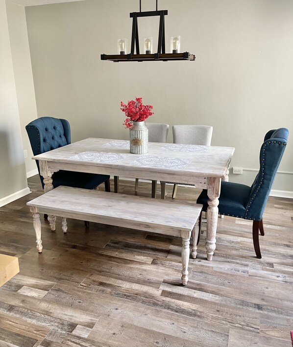 A dining table with a bench, two chairs, a vase with flowers, and a hanging light fixture. - Perfect Wilmington Getaway • 5 Min to Beach, Downtown & UNCW (Wilmington)