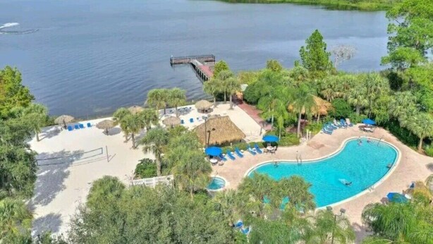 Un complexe hôtelier doté d’une piscine entourée de palmiers et d’une jetée qui s’avance sur un lac.