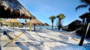 Une plage avec des hamacs et des parasols en chaume.