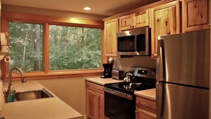 A kitchen with wooden cabinets, a stainless steel refrigerator, a microwave, a stove, and a sink. - Quiet & Peaceful (Galena)