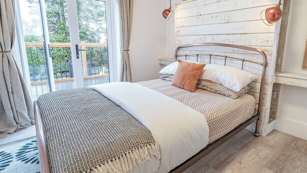A bedroom with a bed, a window, a curtain, a lamp, and a wall with a picture frame. - 3 bedroom accommodation in Llanboidy (Llanboidy)