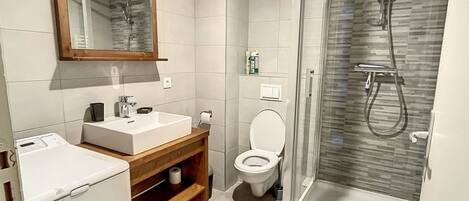 Une salle de bain moderne avec une douche à parois de verre, des toilettes et un lavabo avec un meuble-vasque en bois.