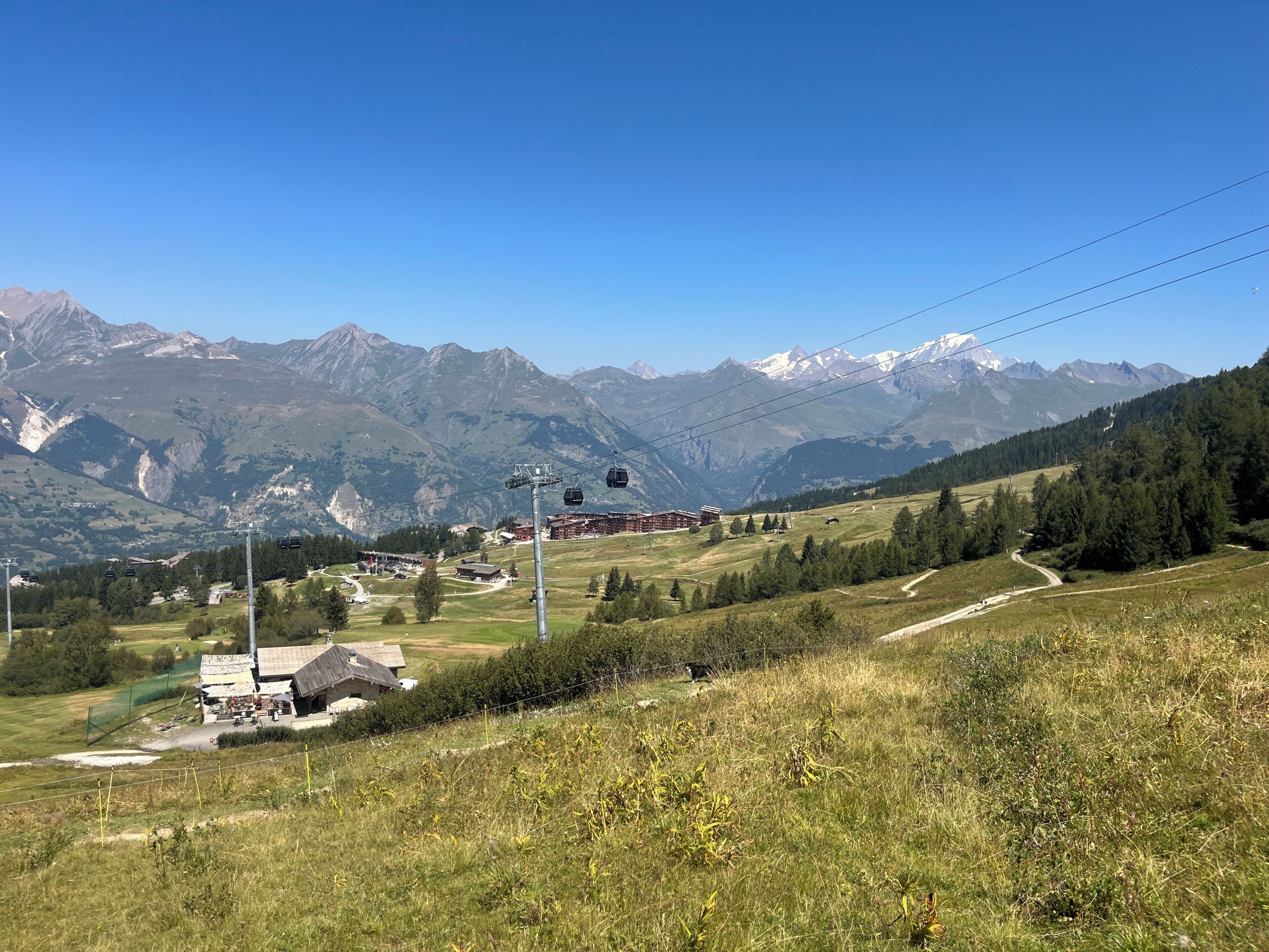 Un paysage de montagne avec un télésiège, des bâtiments et un ciel dégagé.