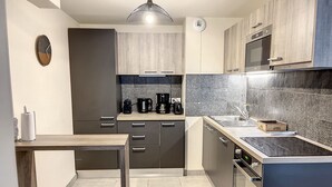 Uma cozinha moderna com armários escuros, bancada de madeira, forno embutido e micro-ondas.