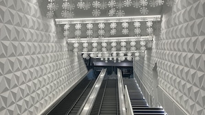 Escalator em edifício moderno com padrões geométricos nas paredes e decorações de flocos de neve.
