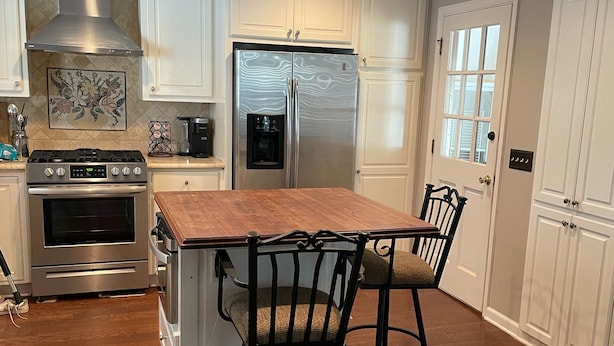 A kitchen with white cabinetry, stainless steel appliances, a wooden island, and a window with a view. - Preakness Corner, Cheerful, cozy 4 bedroom home (Marietta)