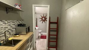 A narrow kitchen with a microwave, sink, and wooden countertop. A red ladder leans against the wall, and a star-shaped decoration hangs on the door. - Preakness Corner, Cheerful, cozy 4 bedroom home (Marietta)