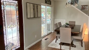 A dining area with a wooden table, chairs, a chandelier, and a stained glass door. - Spacious Custom Retreat with a Pool! (Central Point)