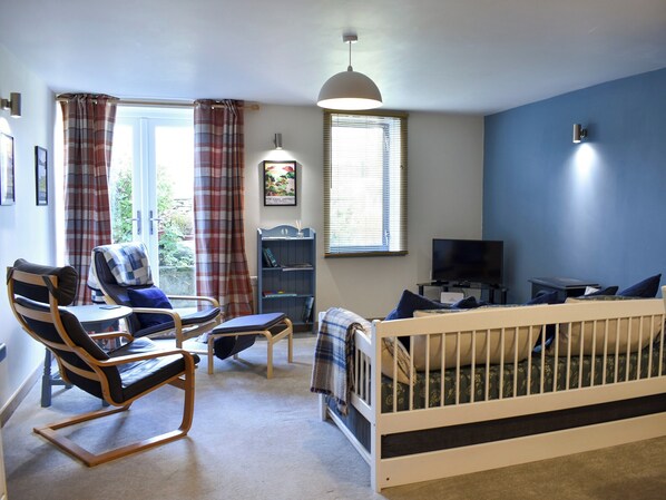 A room with a crib, a rocking chair, a television, and a bookshelf. - A modern ground floor apartment, surrounded by all that Cumbria has to offer. (Shap, near Penrith)