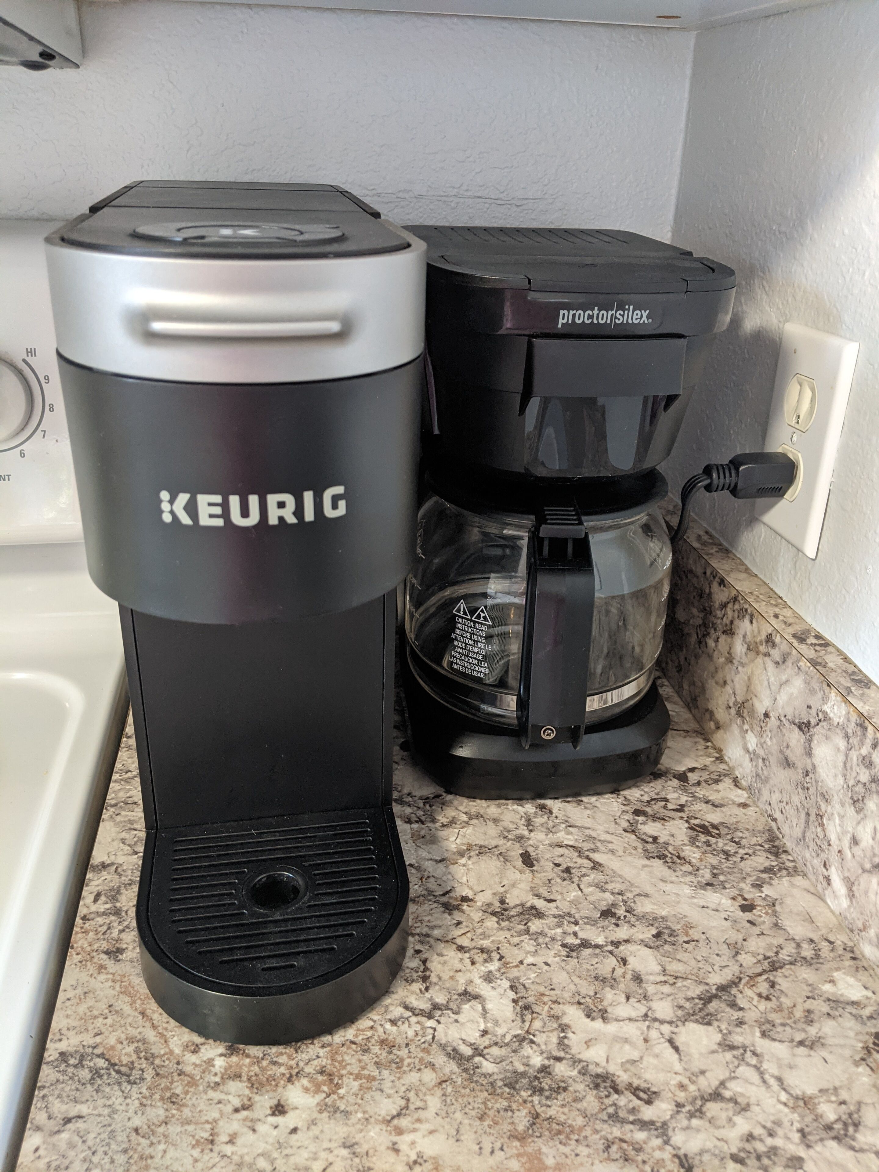Une machine à café Keurig et une cafetière sur un plan de travail de cuisine.