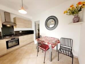 A modern kitchen with a dining area, featuring a stove, oven, and a round mirror above the table.