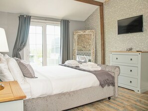 A bedroom with a bed, a dresser, a mirror, and a television.