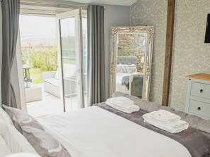 A bedroom with a bed, a large mirror, a nightstand, and a view of a balcony.