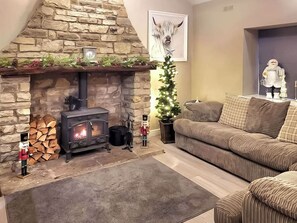 A cozy living room with a stone fireplace, a sofa, and a Christmas tree.