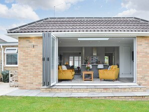 Ein modernes Haus mit einer Terrassenanlage, ausgestattet mit zwei gelben Sesseln und einem kleinen Tisch.