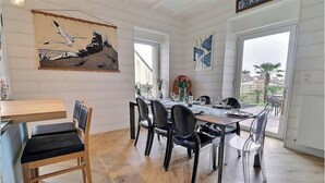 Un comedor con una mesa de madera, sillas negras y un cuadro grande de un tiburón en la pared.