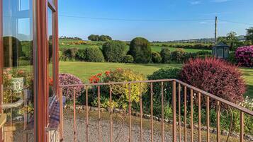 A garden view with a gravel pathway, manicured hedges, and a gazebo.