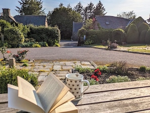 A garden with a paved path, a wooden bench, and a book and mug on the bench. - 3 bedroom accommodation in Stonehaven (Stonehaven)