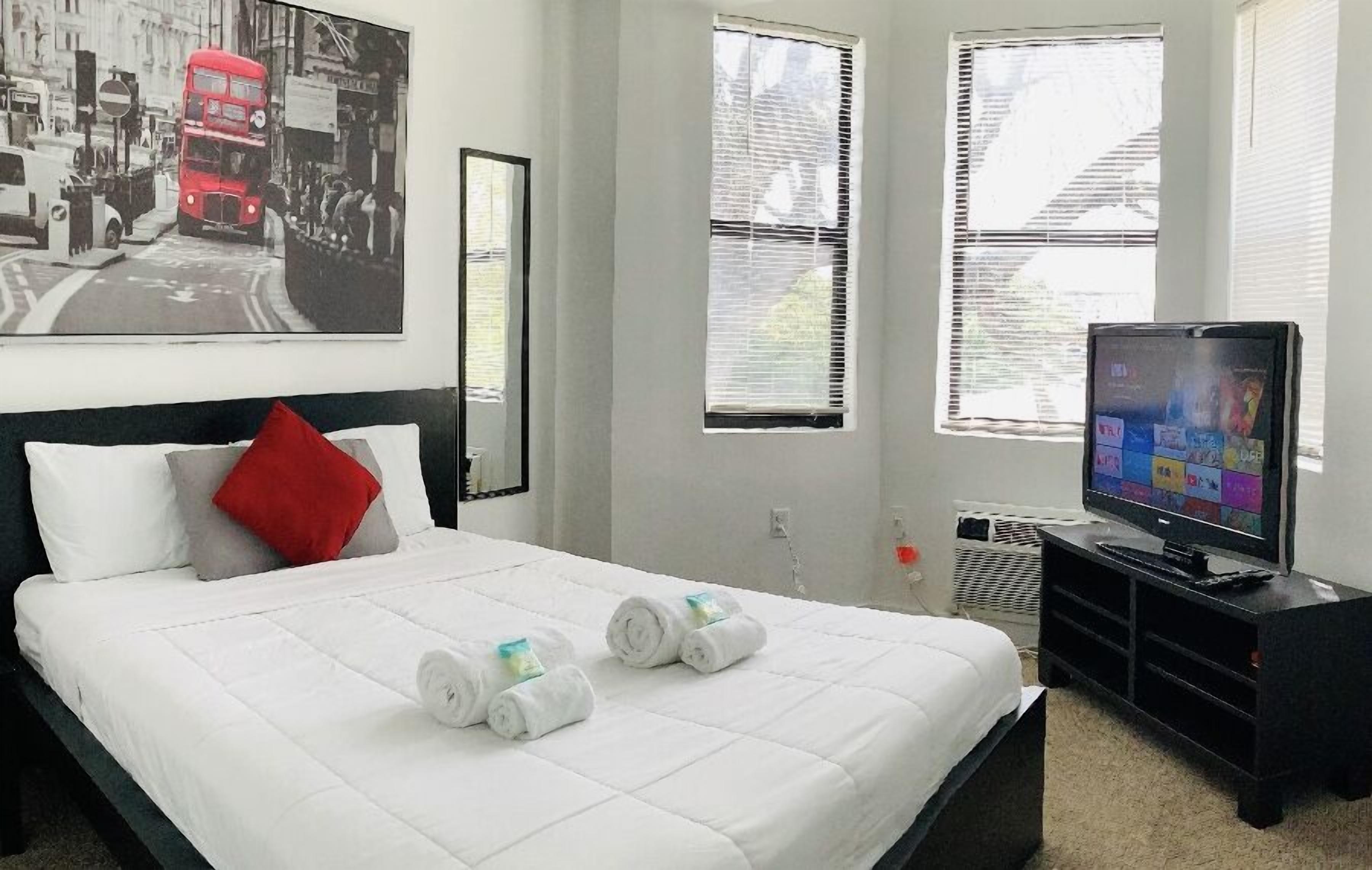 Quarto de hotel com cama, televisão e janela com persianas.