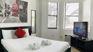 Une chambre d’hôtel avec un lit, une télévision et une fenêtre avec des stores.