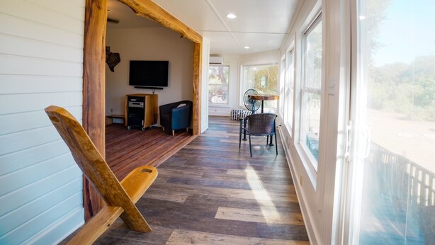 A corridor with a wooden bench, a TV, and a table with chairs. - The Lodge on Salado Creek includes golf cart (Salado)