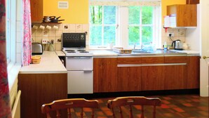 A kitchen with wooden cabinets, a white stove, and a window with a view of greenery.