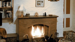 A cozy living room with a brick fireplace, a bookshelf, and a comfortable armchair.