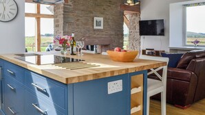 A modern kitchen with a wooden island, stone wall, and a large window. - 3 bedroom accommodation in Dundee (Dundee)