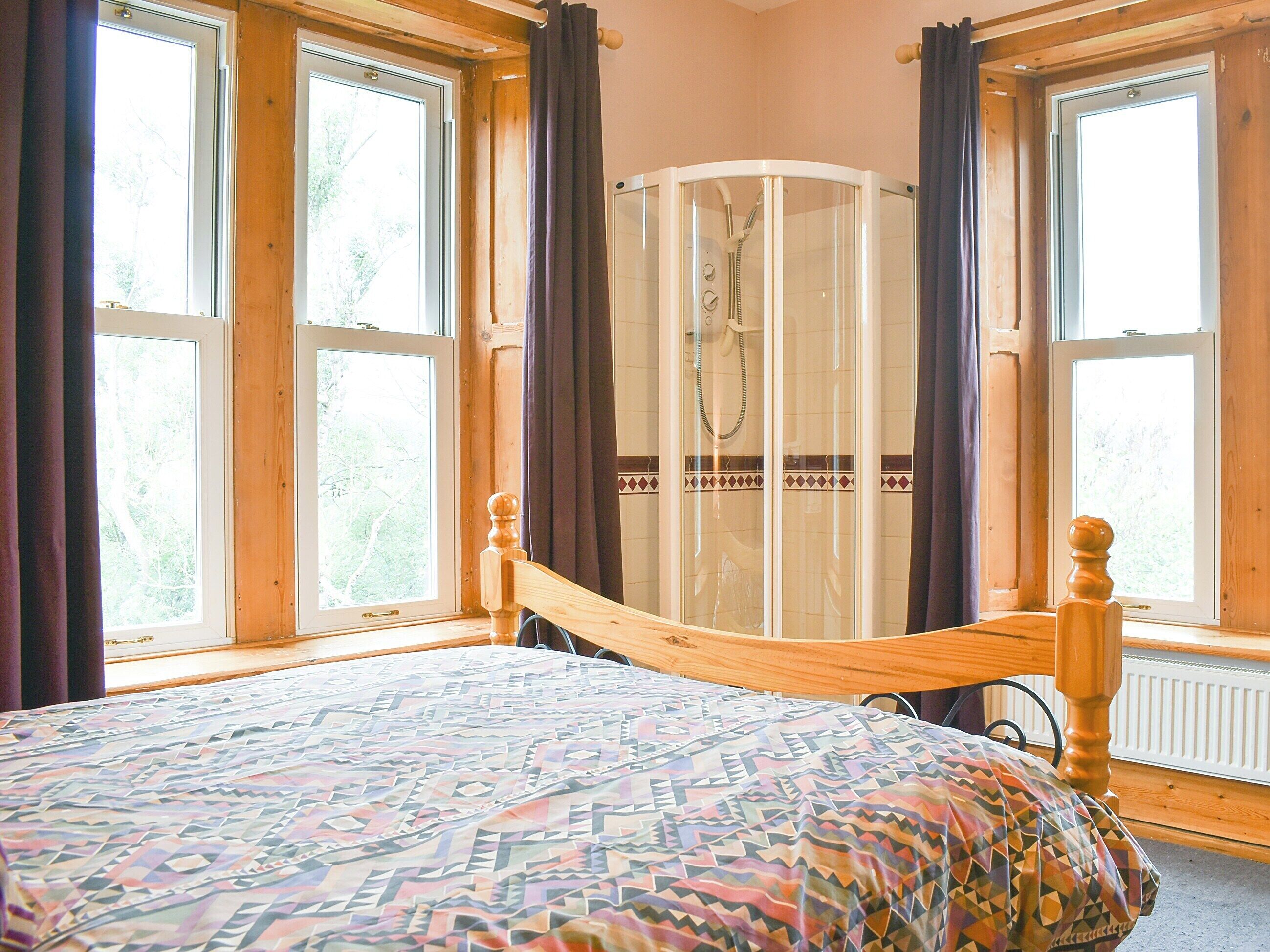 Une chambre à coucher avec un lit, un espace douche et de grandes fenêtres.