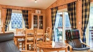 Une pièce chaleureuse aux murs en bois, avec une table à manger, des chaises et un fauteuil à bascule.