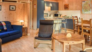 Une pièce chaleureuse avec un canapé bleu, une table à manger en bois et un coin cuisine équipé d’un four à micro-ondes et de placards.