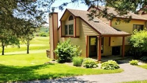 A two-story house with a front porch, a chimney, and a well-maintained lawn. - REMODELED! 2B/2B, Deck off10th GOLF Green, Dog Friendly, Pool, WIFI, in Resort! (Galena)