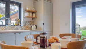 Colazione servita con moka, croissant e altri prodotti da colazione su un tavolo con sedie.