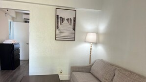 Quarto com uma mesa de centro de madeira, um sofá, uma luminária e um quadro na parede.