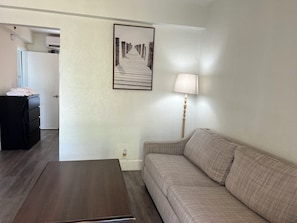 Une pièce avec une table basse en bois, un canapé, une lampe et un tableau encadré au mur.